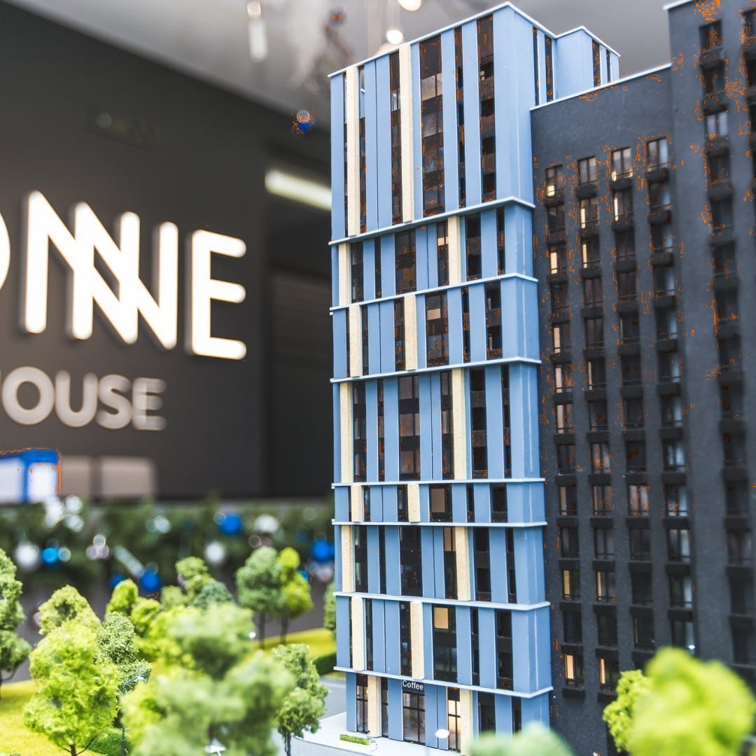 Макет житлового комплексу One House біля вивіски у відділі продажів